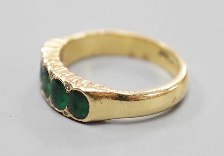 A modern 18ct gold and graduated five stone emerald set half hoop ring, with diamond chip spacers, size Q/R, gross weight 7.5 grams.